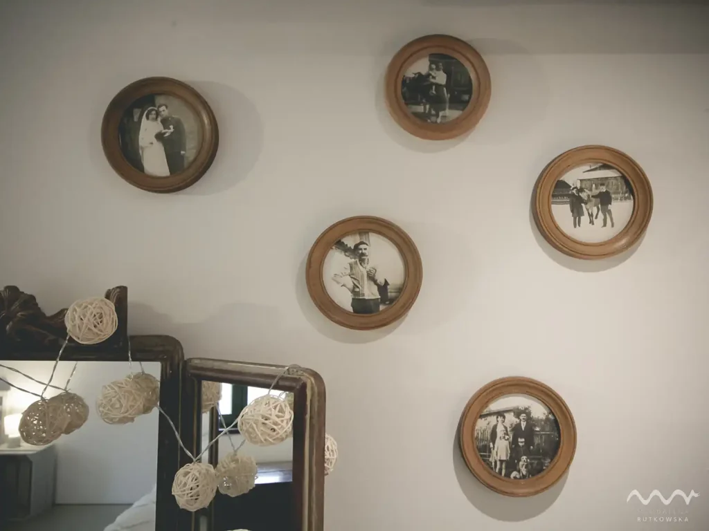Poddasze, historia. Detal na Poddaszu Łuby Siedem: Czarno-białe, zabytkowe zdjęcia dawnych mieszkańców domu w okrągłych, drewnianych ramkach, symbolizujące historię i lokalność w Borach Tucholskich.