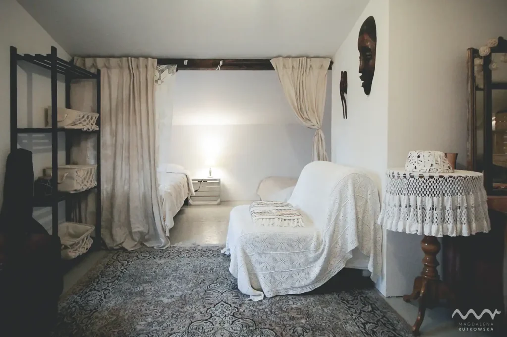 Poddasze, nocleg. Przytulna alkowa z łóżkami, oddzielona zasłonami, na Poddaszu Łuby Siedem. Wnętrze w stylu rustykalno-nowoczesnym, z jasnymi barwami i drewnianymi detalami. Nocleg w Borach Tucholskich.
